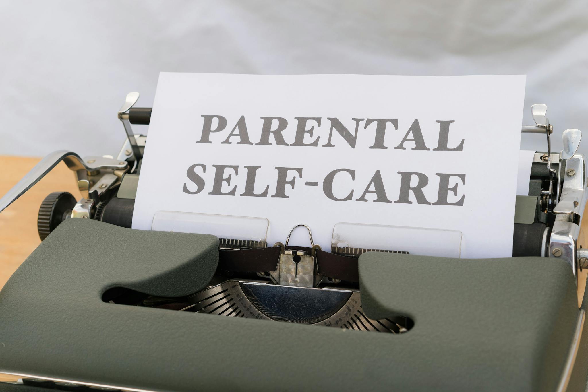 Close-up of a typewriter with the text 'Parental Self-Care.'
